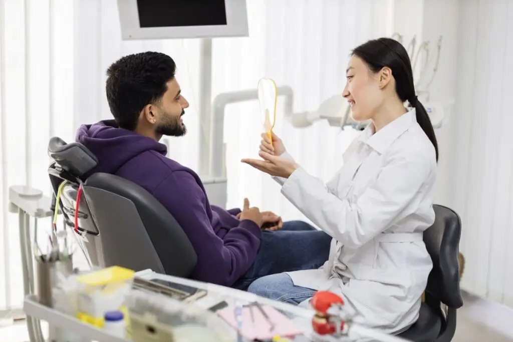 happy-young-bearded-man-enjoying-his-beautiful-too-2024-12-13-02-32-56-utc - Exceptional Dentistry Young Man talks about oral wellness with dentist